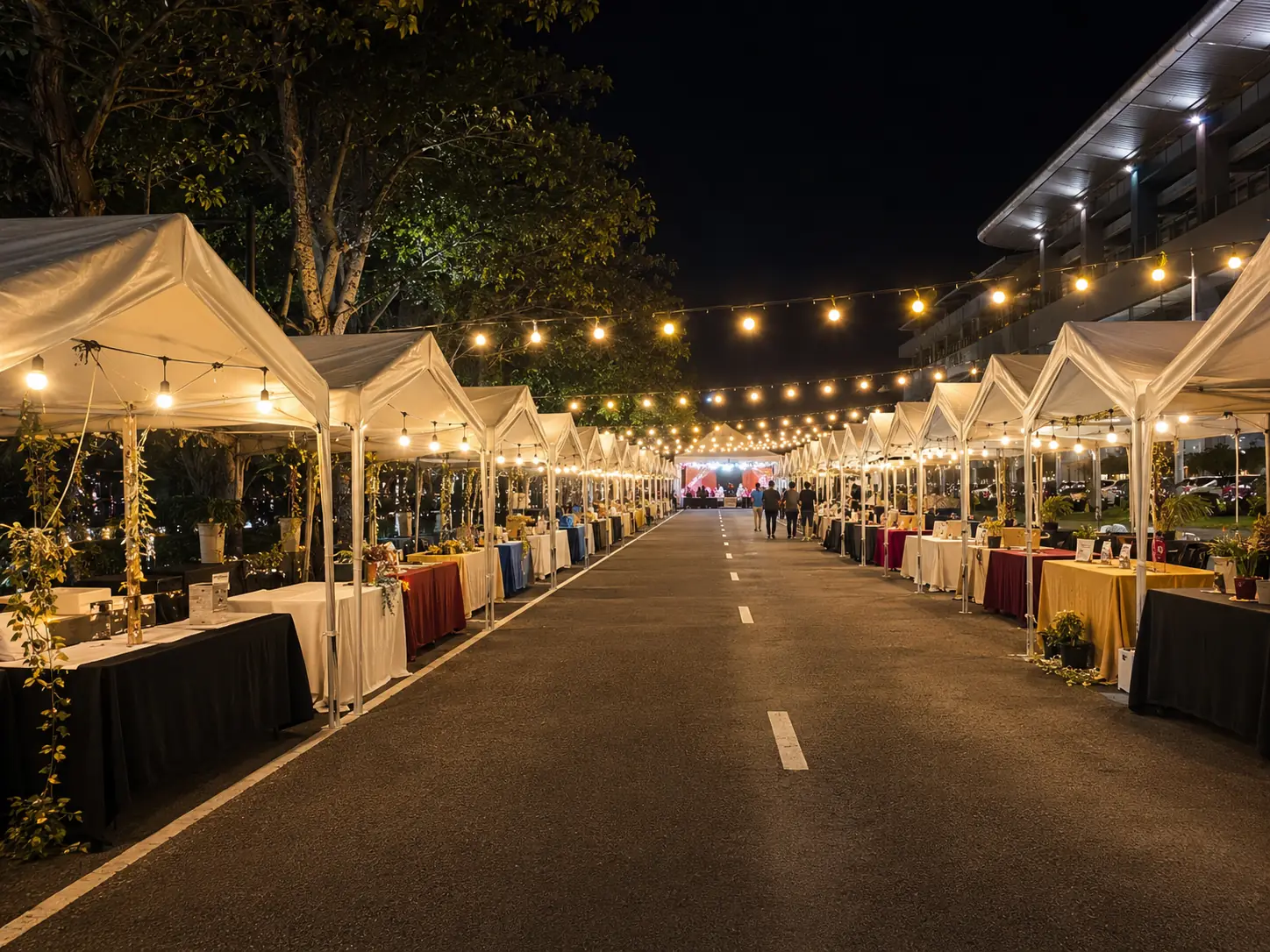 Festive night market in Malaysia with bazaar marquee tents, warm string lights, decorated vendor tables and a central walkway for visitors