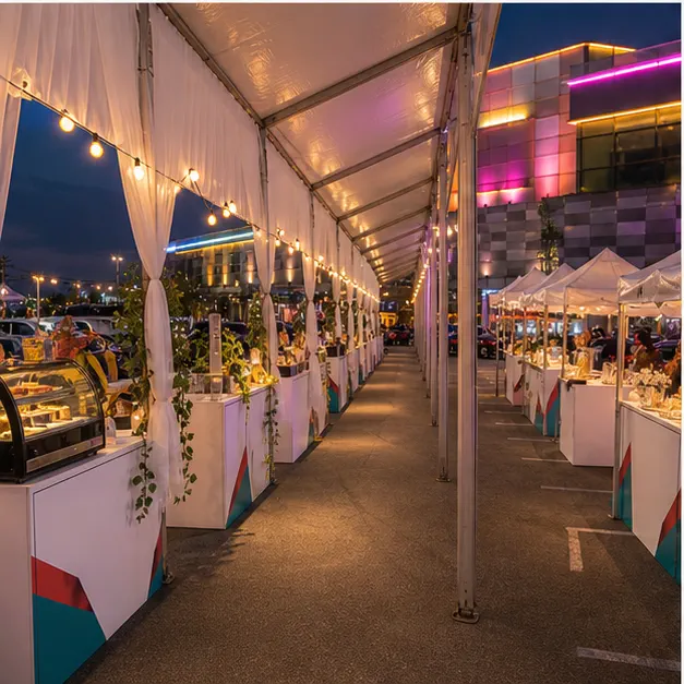 Side view of vendor booth rows and food-stall style tents with lighting towers, clear aisle and guest circulation