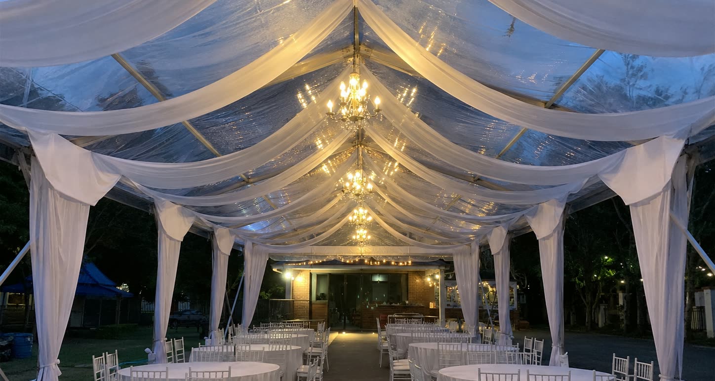 Evening clear roof marquee dining setup with pearl drapes, chandeliers and round white tables