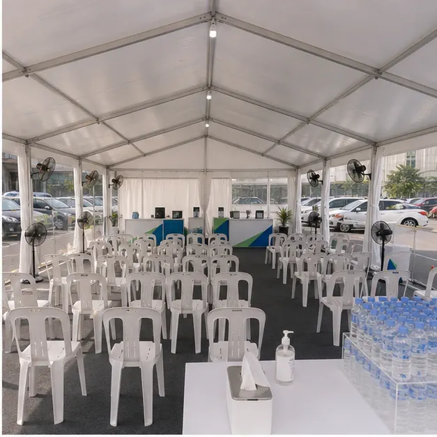 Inside view of a waiting marquee with plastic chairs, standing fans, side walls, support counters and water table