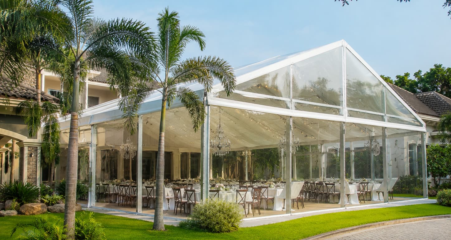Daytime garden transparent marquee with palm trees, clear walls and dining setup