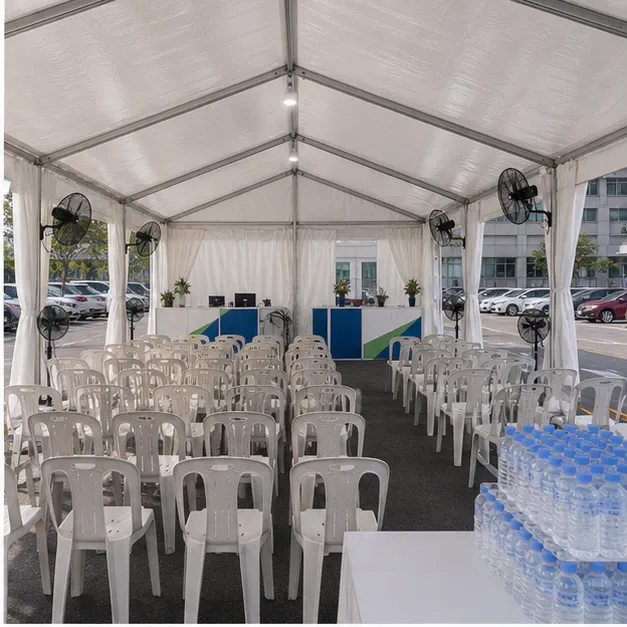 Inside view of a hospital waiting marquee with chairs, standing fans, water station, side panels and support counters