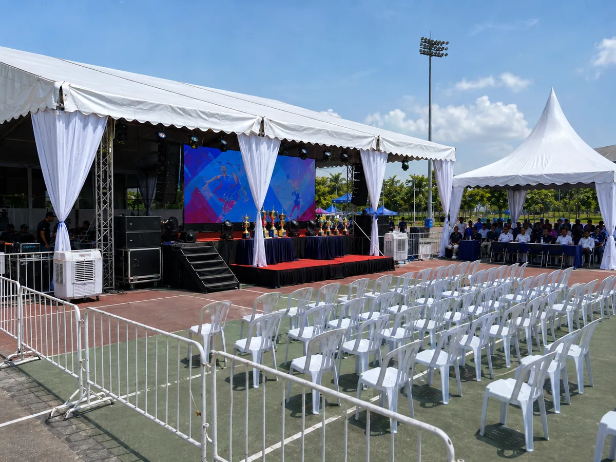 Covered marquee stage setup at Kompleks Sukan Pandamaran with LED screen, sound system, VIP canopy, cooling units and arranged spectator chairs