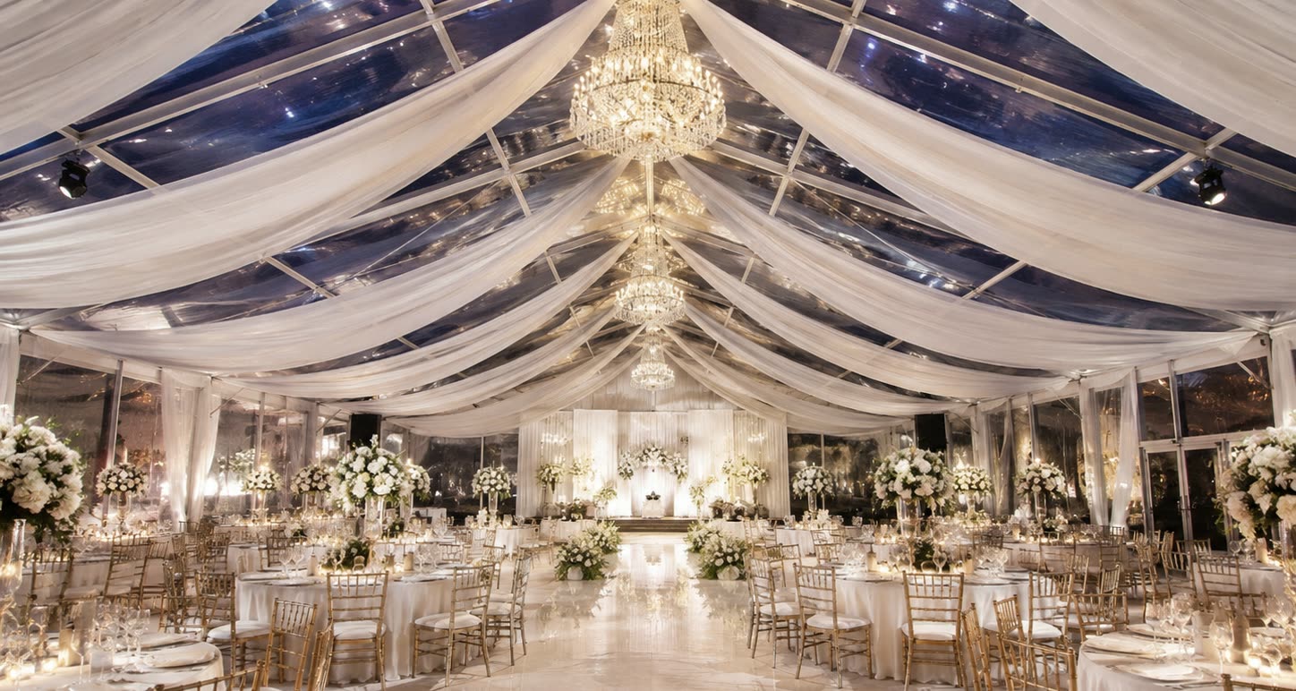 Luxury clear roof marquee banquet interior with gold chairs, chandeliers and pearl drapes