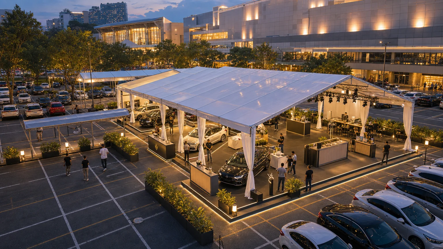 High angle view of an outdoor mall roadshow layout with clear span marquee, car display bays, black flooring, demo counters and car park access