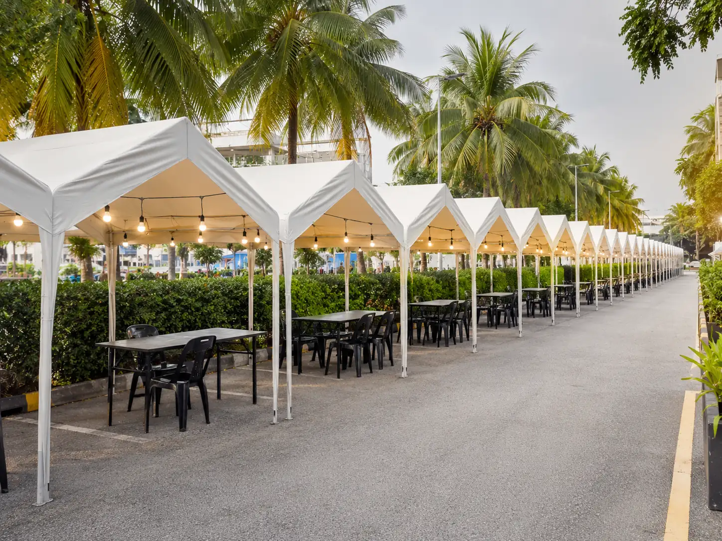 Clean pop-up bazaar canopy rental setup in Malaysia with empty stall tents, tables, chairs and palm-lined outdoor event space ready for vendors