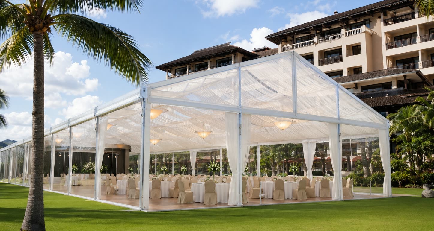 Clear roof marquee on a resort lawn with pearl drapes, palm trees and dining tables