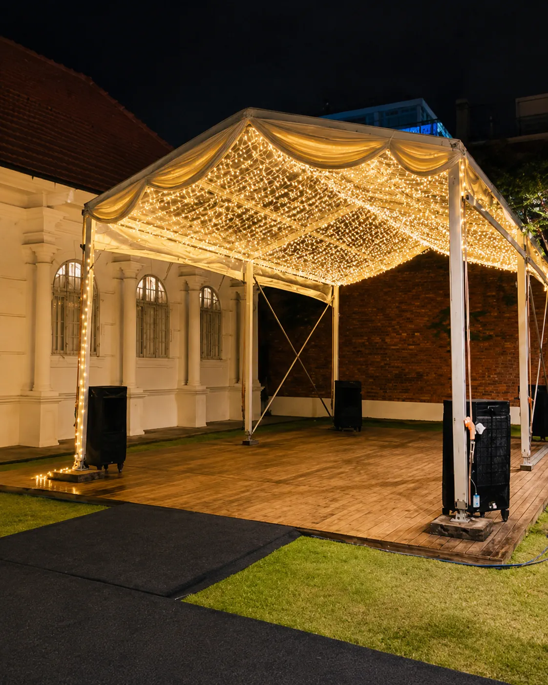 Small backyard clear roof marquee for an intimate gathering with warm fairy lights, soft drapes, timber flooring and house compound access