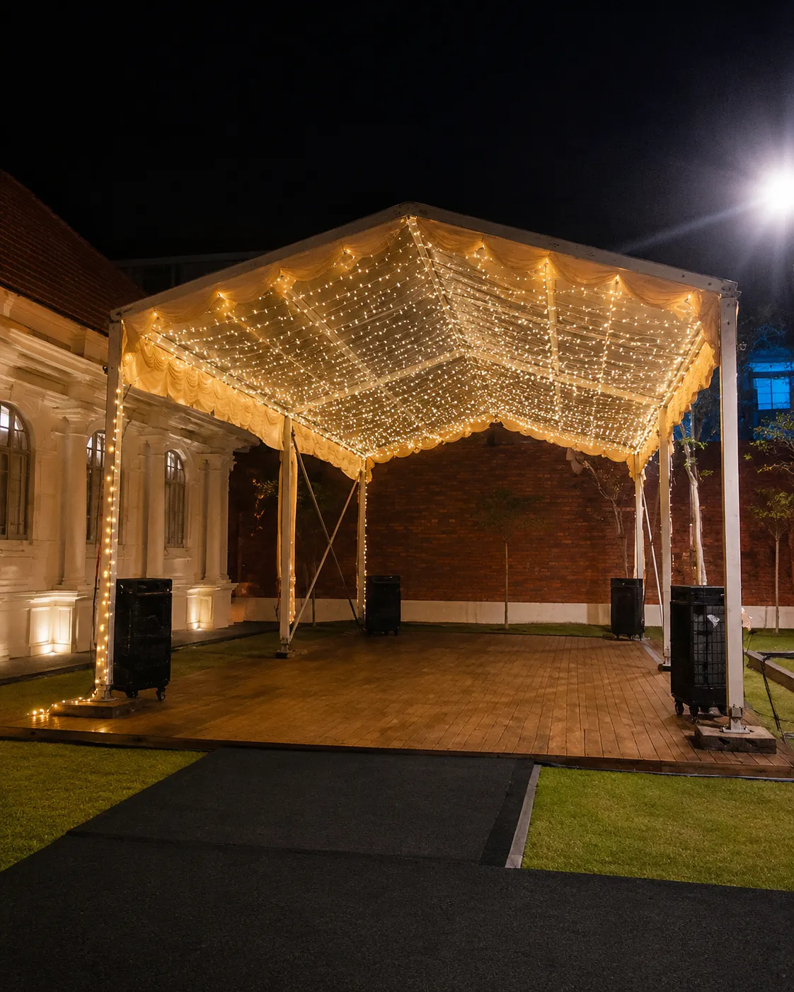 Small backyard clear roof marquee for an intimate gathering behind a house with warm fairy lights, soft drapes, timber flooring and compact guest area