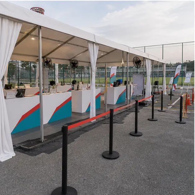 Side view of a white marquee registration canopy with check-in counters, queue barriers and clear pedestrian route