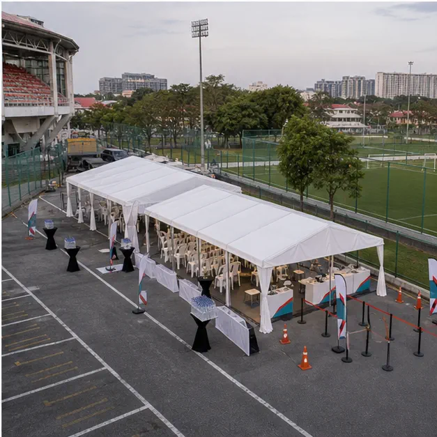 High angle view of a stadium compound event layout with white marquee, registration canopy, seating zone and sports field access