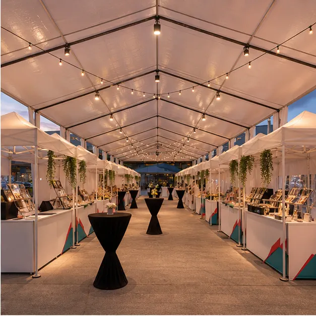 Inside view of modular marquee vendor rows with product tables, cashier counters, lighting and clear walking aisle