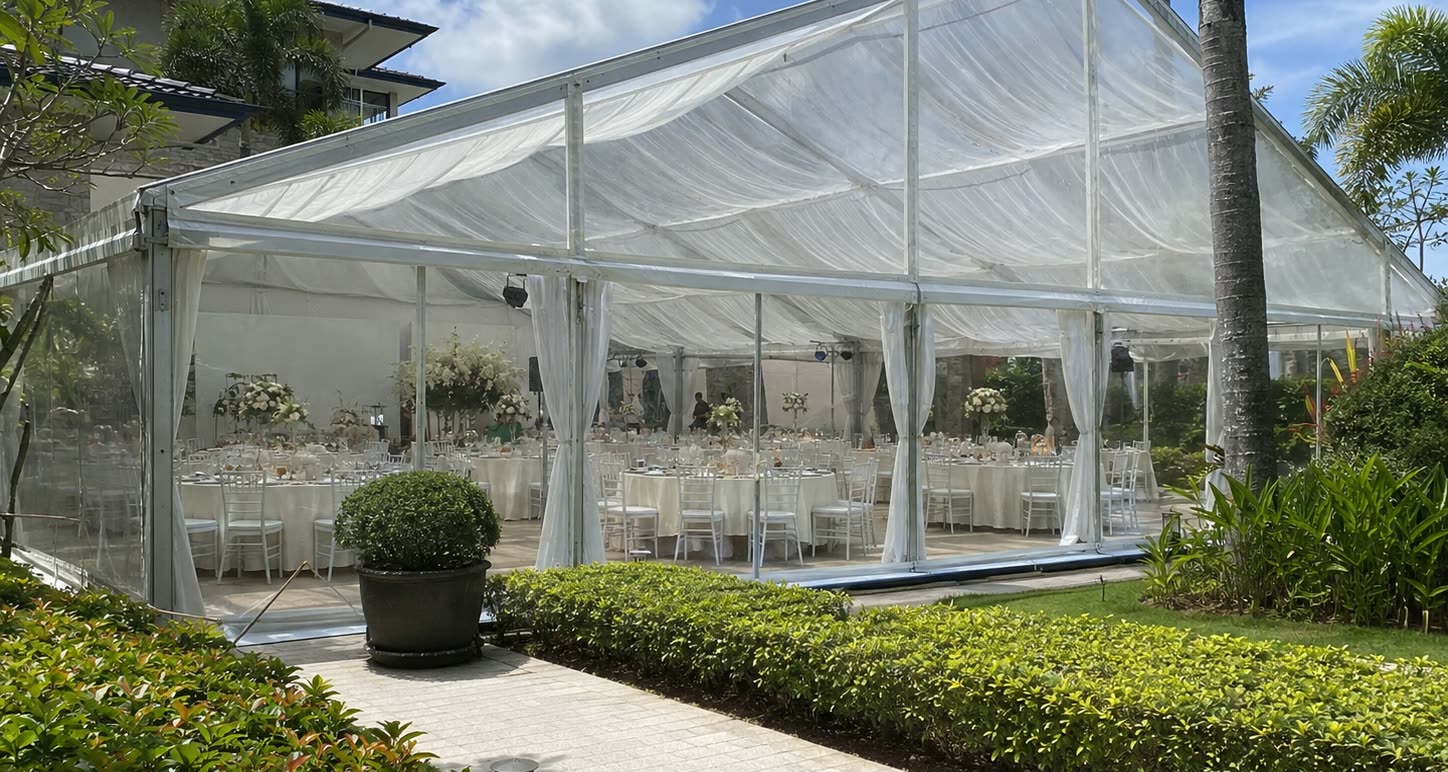 Daytime transparent garden marquee with pearl drapes, hedges, white dining setup and palm trees
