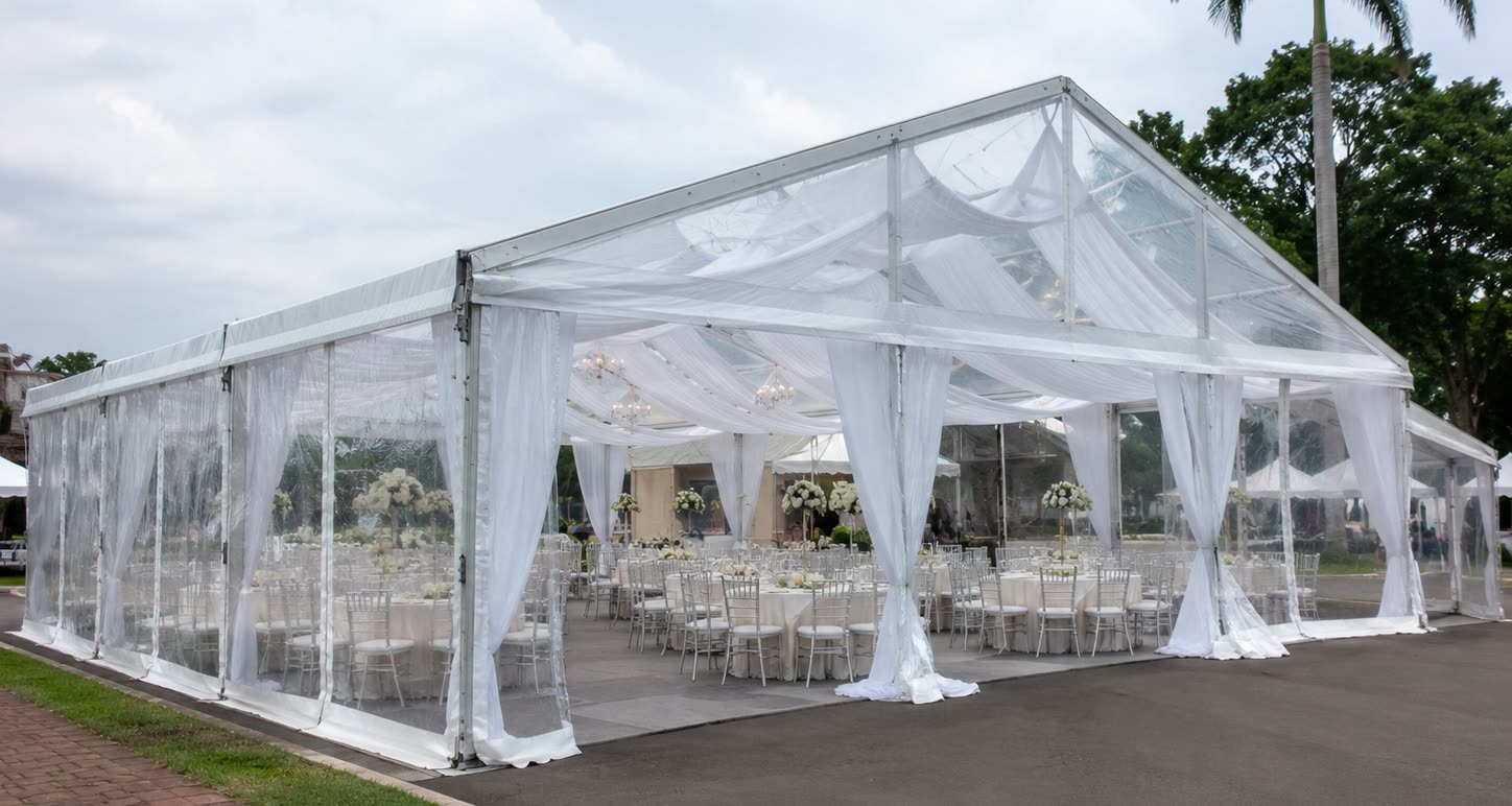 Transparent pearl dining marquee exterior with clear walls, white chairs and floral centrepieces