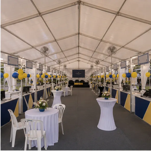 Inside view of a campus career fair marquee with booth canopy rows, counters, lounge tables, fans and clear aisle