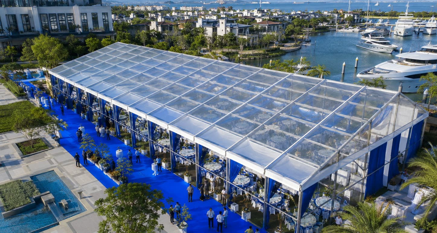 Aerial view of a large waterfront clear span marquee with blue carpet and dining setup